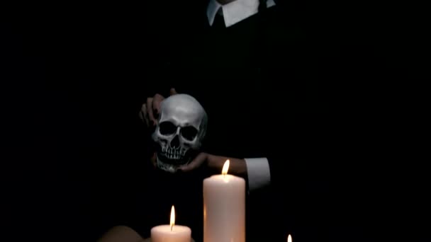 Бледная девушка сидит возле свечей и черепа — стоковое видео