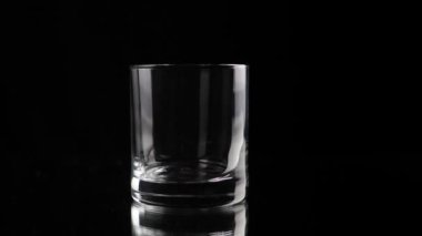 Ice cube falling into empty glass