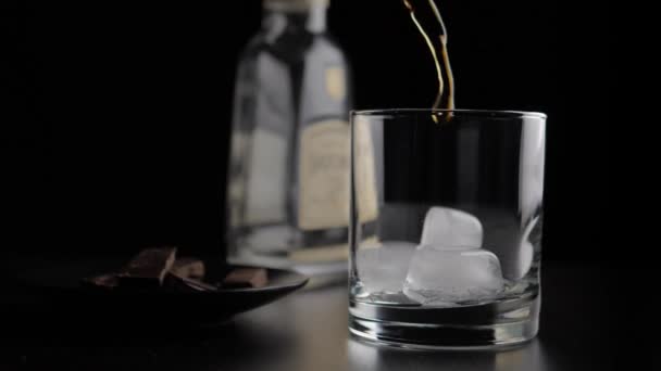 Наливание коричневого спирта в стекло — стоковое видео