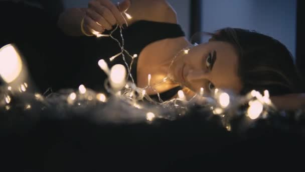 Mooie jongedame op verdieping met lichte decoratie — Stockvideo