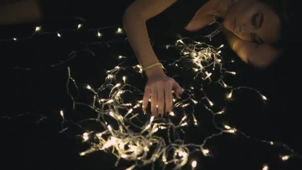 Mujer hermosa joven en el piso con decoración de luz — Vídeo de stock