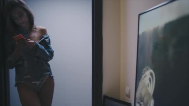 Молодая женщина со смартфоном в коридоре — стоковое видео