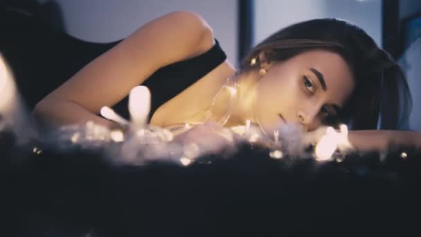 Mujer hermosa joven en el piso con decoración de luz — Vídeos de Stock