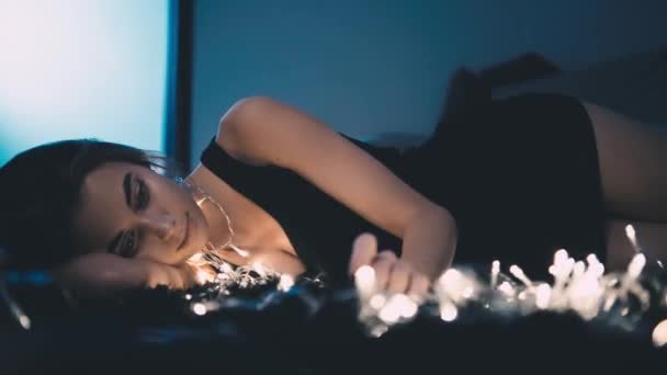 Νεαρή όμορφη γυναίκα στο πάτωμα, με φωτεινή διακόσμηση — Αρχείο Βίντεο
