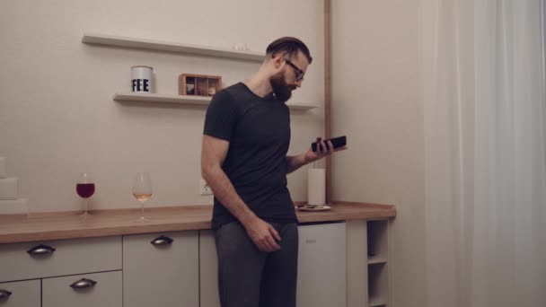 Бородатый мужчина со смартфоном реагирует на контент — стоковое видео