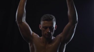 Genç, formda adam dambıl presi yapıyor.