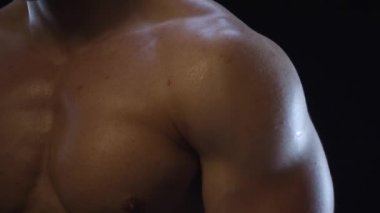 Genç formda adam poz veriyor, omuz kaslarını gösteriyor, yavaş çekim