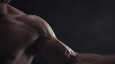 Genç adam kaslarını gösteriyor, yakın çekim, yavaş çekim, kusursuz döngü.