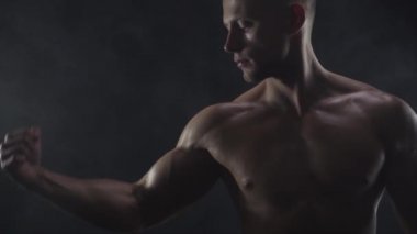 Genç, formda adam bisepsi gösteriyor, yakın çekim, yavaş çekim.