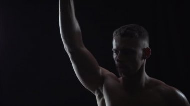 Tek elle dambıl, siluet ve ağır çekimde ağırlık kaldıran genç adam.