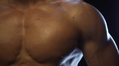 Genç zinde adam poz veriyor, göğüs kaslarını gösteriyor, yavaş çekim.