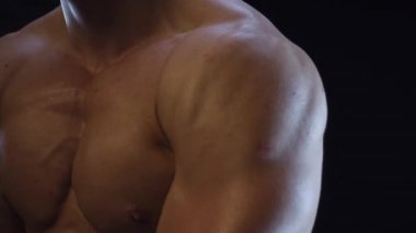 Genç formda adam poz veriyor, omuz kaslarını gösteriyor, yavaş çekim