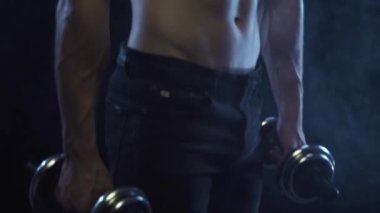 Siyah arka planda dambıllar tutan genç ve formda bir adam.