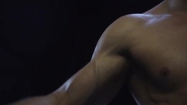 Genç adam kaslarını gösteriyor, yakın çekim, yavaş çekim, kusursuz döngü.