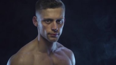 Siyah arka planda dambıllar tutan genç ve formda bir adam.