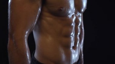 Genç fit adam poz veriyor, karın kaslarını gösteriyor, yavaş çekim.