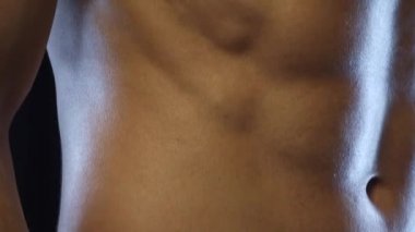 Genç fit adam poz veriyor, karın kaslarını gösteriyor, yavaş çekim.