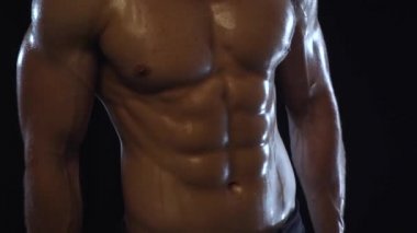 Genç fit adam poz veriyor, karın kaslarını gösteriyor, yavaş çekim.