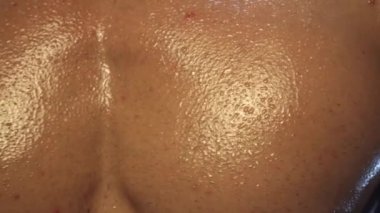Genç fit adam poz veriyor, göğüs kaslarını terle gösteriyor, ağır çekimde.