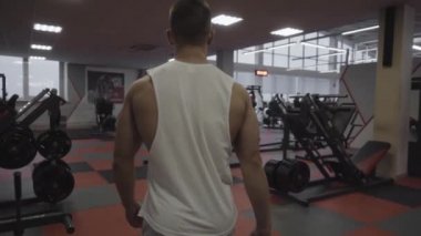 Kaslı adam spor salonuna giriyor.