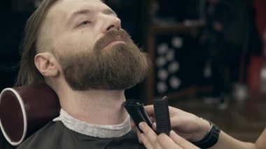 Berber dükkanındaki yakışıklı sakallı genç adam, 50 fp ile 25 fps arası yavaş çekim. Sakal kırpma