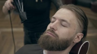 Berber dükkanındaki yakışıklı sakallı genç adam, 50 fp ile 25 fps arası yavaş çekim. Saç kesimi.