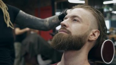 Berber dükkanındaki yakışıklı sakallı adam, 50 fp ile 25 fps arası yavaş çekim. Tıraş bıçağıyla saç kesmek