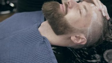 Berber dükkanındaki yakışıklı sakallı genç adam, 50 fp ile 25 fps arası yavaş çekim. Saç yıkama işlemi