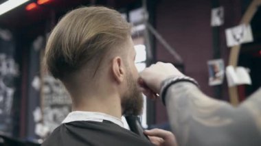 Berber dükkanındaki genç yakışıklı sakallı adam, sığ bir tarla derinliği