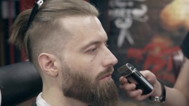 Berber dükkanındaki genç yakışıklı sakallı adam, sığ bir tarla derinliği