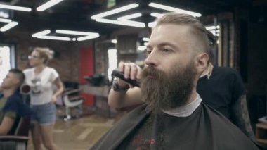 Berber dükkanındaki genç yakışıklı sakallı adam, sığ bir tarla derinliği