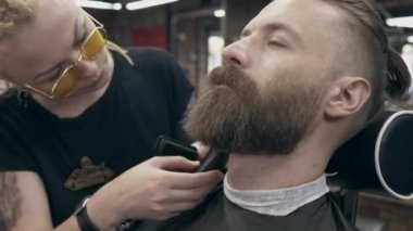 Berber dükkanındaki genç yakışıklı sakallı adam, sığ bir tarla derinliği