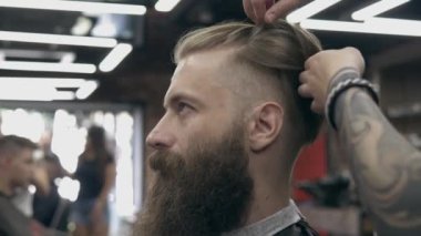 Berber dükkanındaki yakışıklı sakallı genç adam, sığ bir tarlada. Saç kesimi.