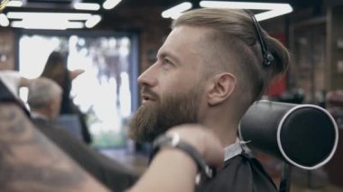 Berber dükkanındaki genç yakışıklı sakallı adam, sığ bir tarla derinliği