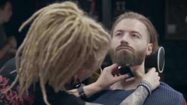 Berber dükkanındaki genç yakışıklı sakallı adam, sığ bir tarla derinliği