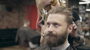 Sakallı yakışıklı bir adam. Rasta saçlı genç bir kadından, ağır çekimde. Saç kesimi.