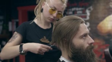 Berber dükkanındaki yakışıklı sakallı genç adam, sığ bir tarlada. Saç kesimi.