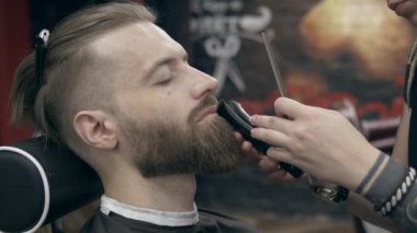 Berber dükkanındaki genç yakışıklı sakallı adam, sığ bir tarla derinliği