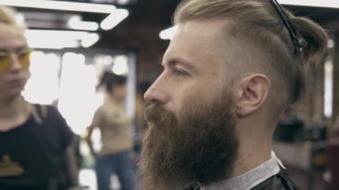 Berber dükkanındaki genç yakışıklı sakallı adam, sığ bir tarla derinliği