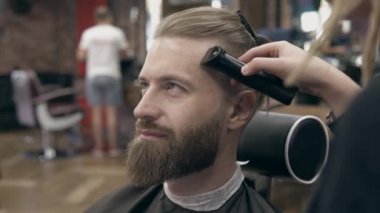 Berber dükkanındaki genç yakışıklı sakallı adam, sığ bir tarla derinliği