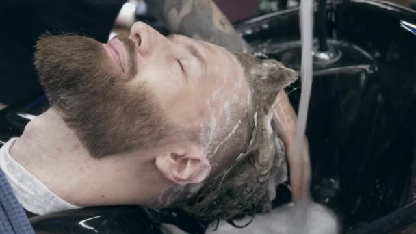 年轻英俊的大胡子男人在理发店 浅浅的田野深处 洗头发的过程 — 图库视频影像