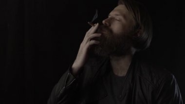 Siyahın üstünde sigara içip, sakallı adam içmek. Yavaş çekim