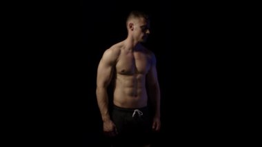 Siyah arka plandaki genç fit adam. Ağır çekim. Yavaşça yakınlaştır