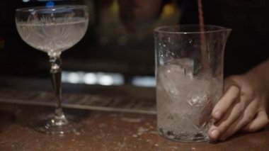 Bar masasında kaşık kaşık buzu boş bardakta karıştırmak. Yakın çekim, yavaş çekim (60 fps 25 fps)