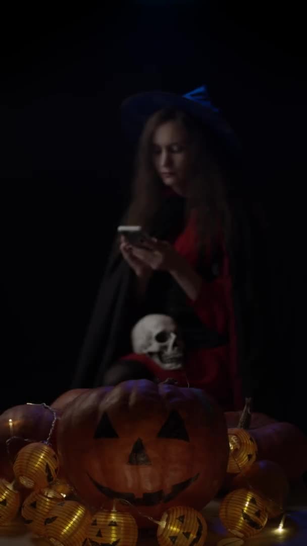Halloween Pumpa Med Träd Och Ung Häxa Med Smartphone Vertikal — Stockvideo