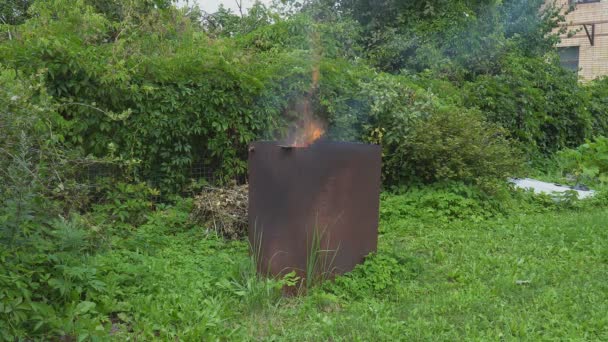 Brandende takken, gesneden struiken en bomen, in de kachel, aangepast aan een grote metalen tank. De vlam barst uit en komt omhoog.. — Stockvideo