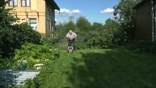Пенсионер стрижет газон на газоне у себя дома — стоковое видео