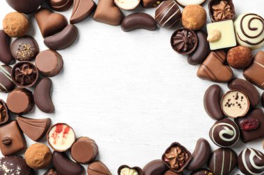 Beyaz ahşap zemin üzerinde farklı lezzetli çikolata şekerleme çerçeve yapılmış