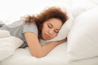 Yatakta uyuyan güzel genç Afrikalı-Amerikalı kadın sabah