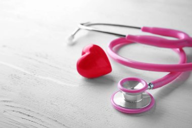 Beyaz ahşap zemin üzerinde stetoskop ve kırmızı kalp. Sağlık kavramı